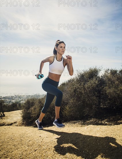 Woman jogging on mountain with water bottle
