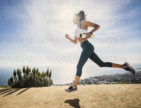 Woman jogging on mountain with water bottle