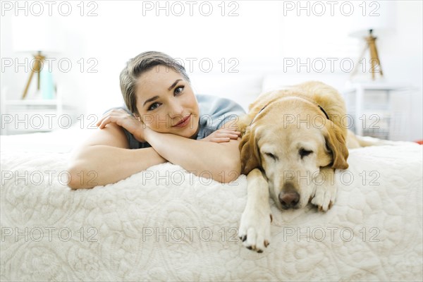 Woman lying on bed with dog