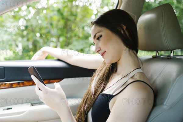 Young woman using smart phone in car