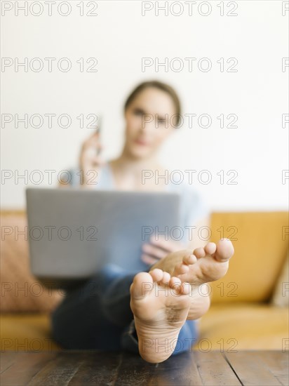 Barefoot woman using laptop