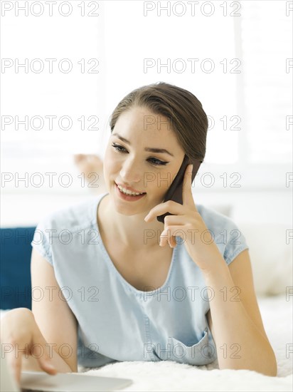 Woman using laptop and smart phone on bed