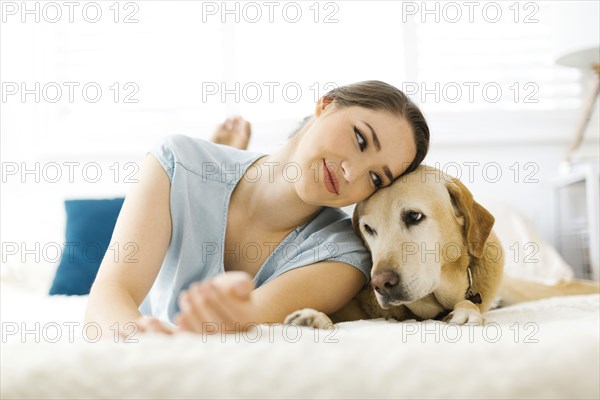 Woman lying on bed with dog