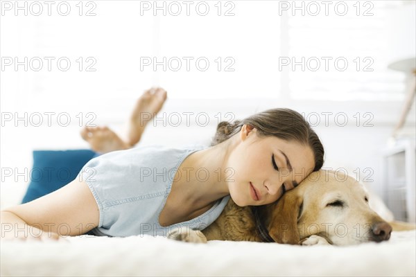 Woman lying on bed with dog