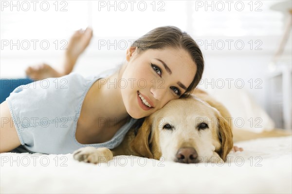 Woman lying on bed with dog