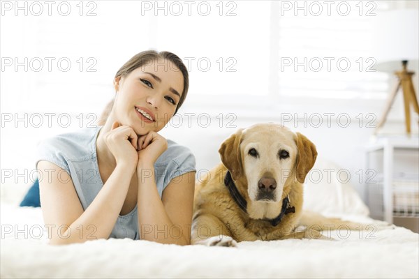 Woman lying on bed with dog