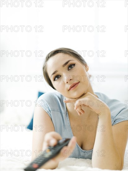 Woman using remote control on bed