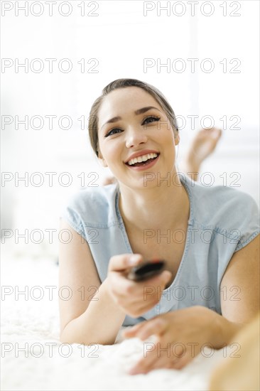 Woman using remote control on bed