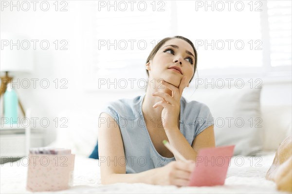 Woman writing in card on bed