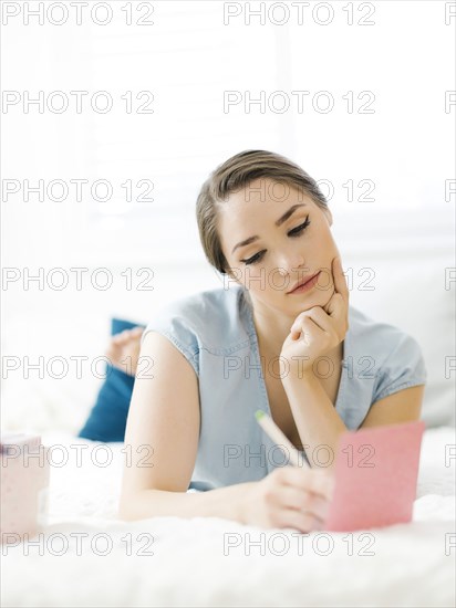 Woman writing in card on bed