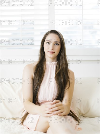 Young woman sitting on bed