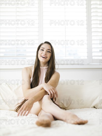 Young woman sitting on bed