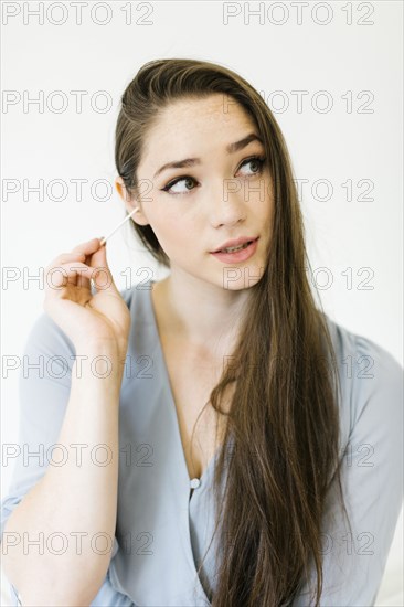 Woman cleaning her ear with cotton bud