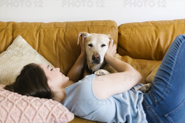 Woman lying on sofa with dog