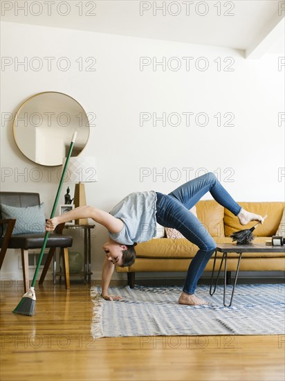 Woman bending over backwards sweeping and dusting