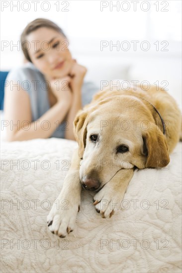 Woman lying on bed with dog