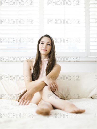 Young woman sitting on bed