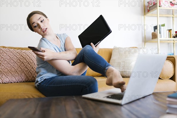 Woman holding smart phone and folder while typing with foot