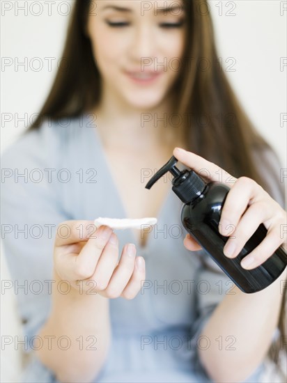 Woman putting skin care onto cotton pad - Photo12-Tetra Images