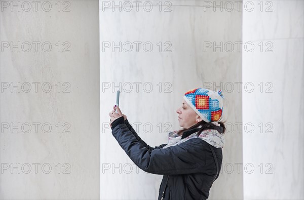 Woman taking photograph with smart phone by pillars