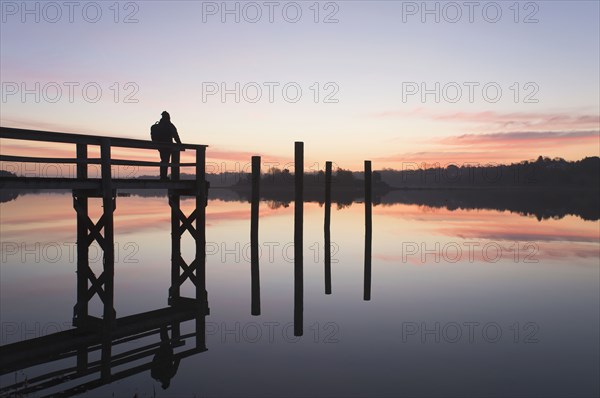 Silhouette of man on pier at sunrise