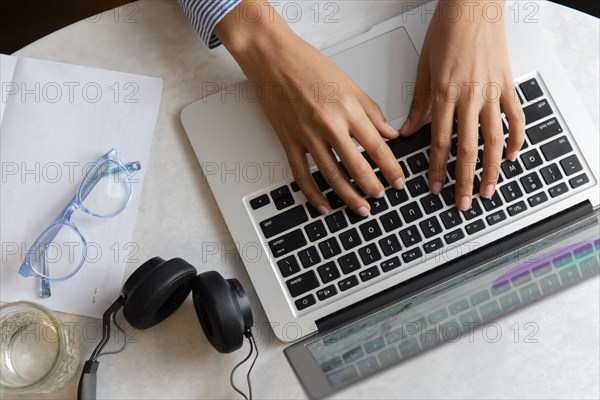 High angle view of young woman's hands typing on laptop