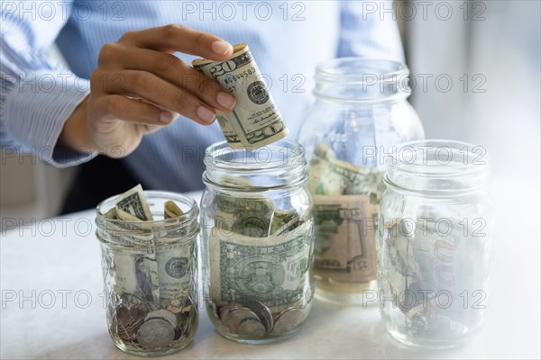 Hand of woman putting money in jar
