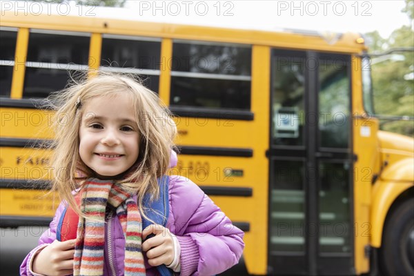 Smiling girl by school bus