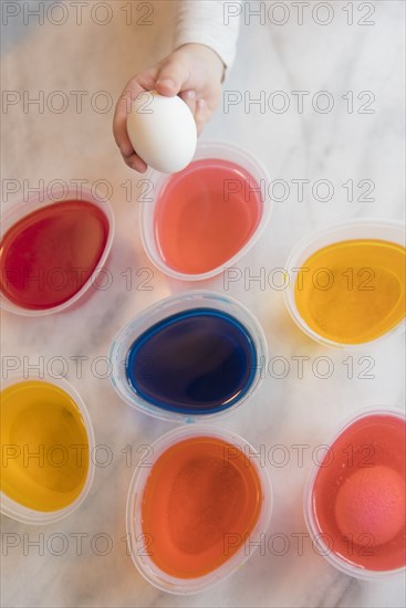 Hand of girl selecting dye for Easter egg