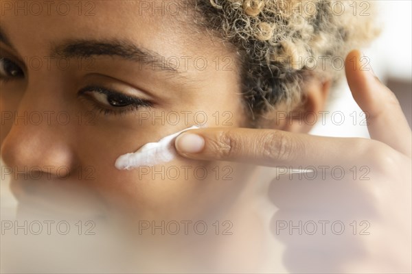 Young woman applying moisturizer