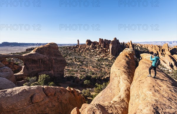 Woman taking photograph while hiking in Arches National Park, Utah, USA