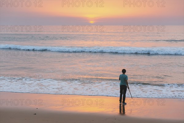 Young man on beach at sunset in Lisbon, Portugal