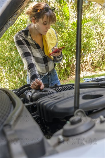 Woman reading on smart phone while repairing car