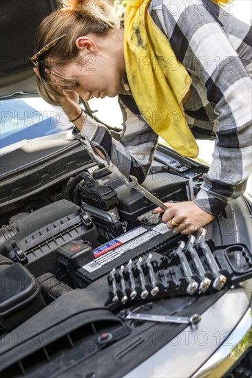 Frustrated woman repairing car