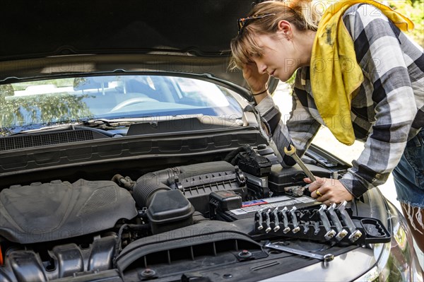 Frustrated woman repairing car