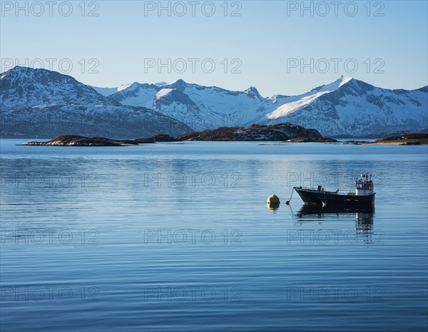 Fishing boat by snow covered mountains in Tromso, Norway