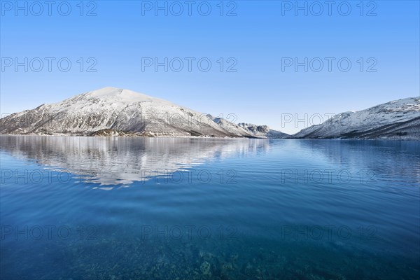 Snow covered hills by sea in Tromso, Norway