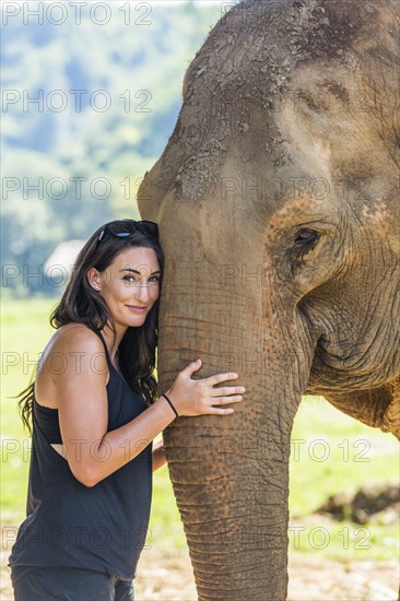 Woman holding trunk of Indian elephant in Chiang Mai, Thailand