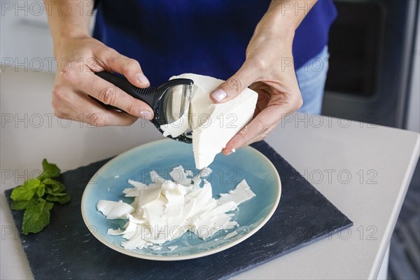 Hands of woman shaving ricotta