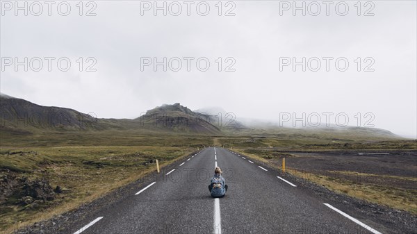 Woman sitting on highway in Iceland
