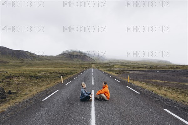 Couple sitting on highway in Iceland