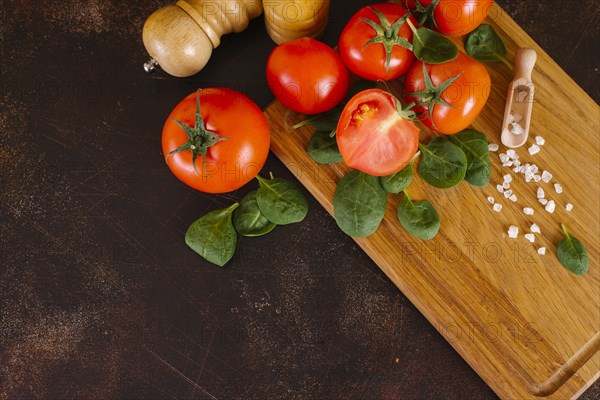 Tomatoes, basil and salt on wooden cutting board