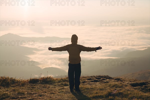 Man with arms outstretched in the Carpathian Mountain Range at sunrise