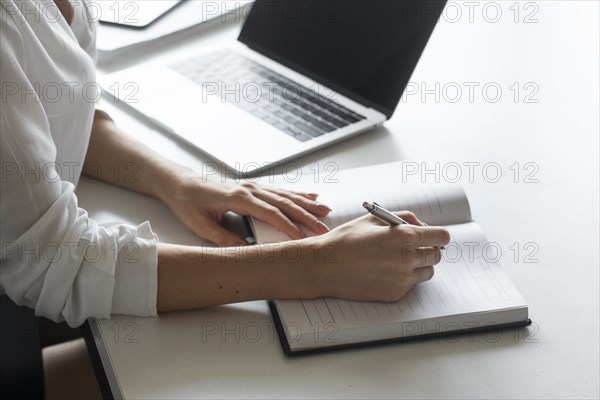 Hand of young businesswoman writing notes at desk