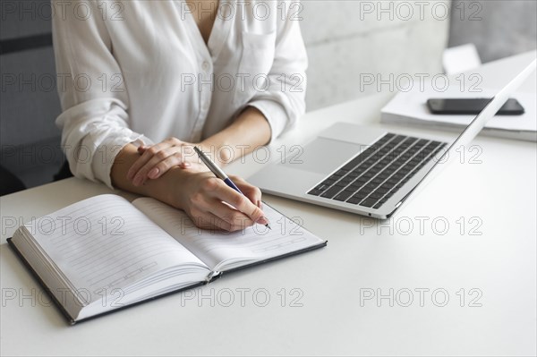 Hand of young businesswoman writing notes at desk