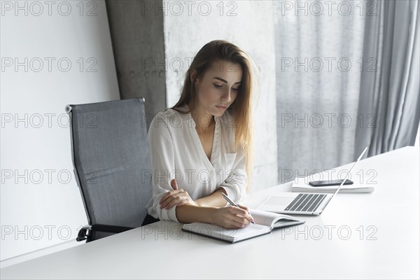 Young businesswoman taking notes at desk