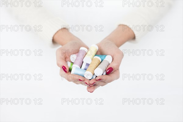 Hands of woman holding spools of cotton