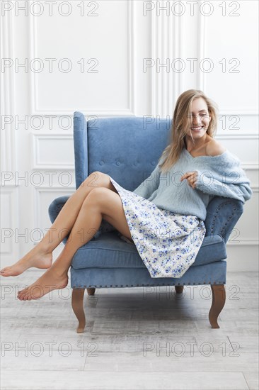 Young woman sitting in blue armchair