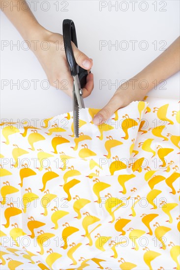 Hands of woman cutting fabric with duck print
