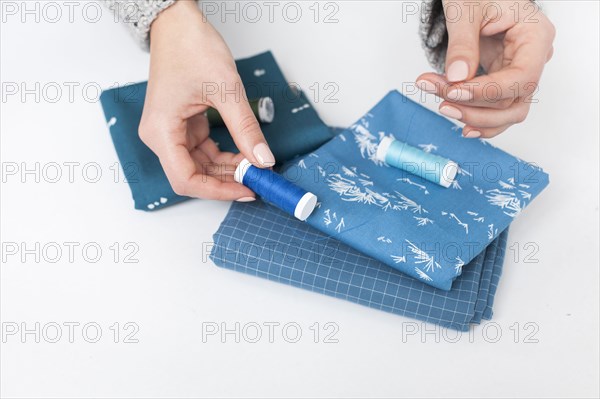 Woman's hand matching thread to blue fabric